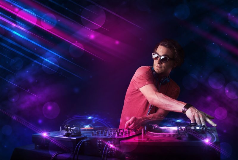 21891955_l-Attractive-young-DJ-playing-on-turntables-with-color-light-effects-e1719563047831