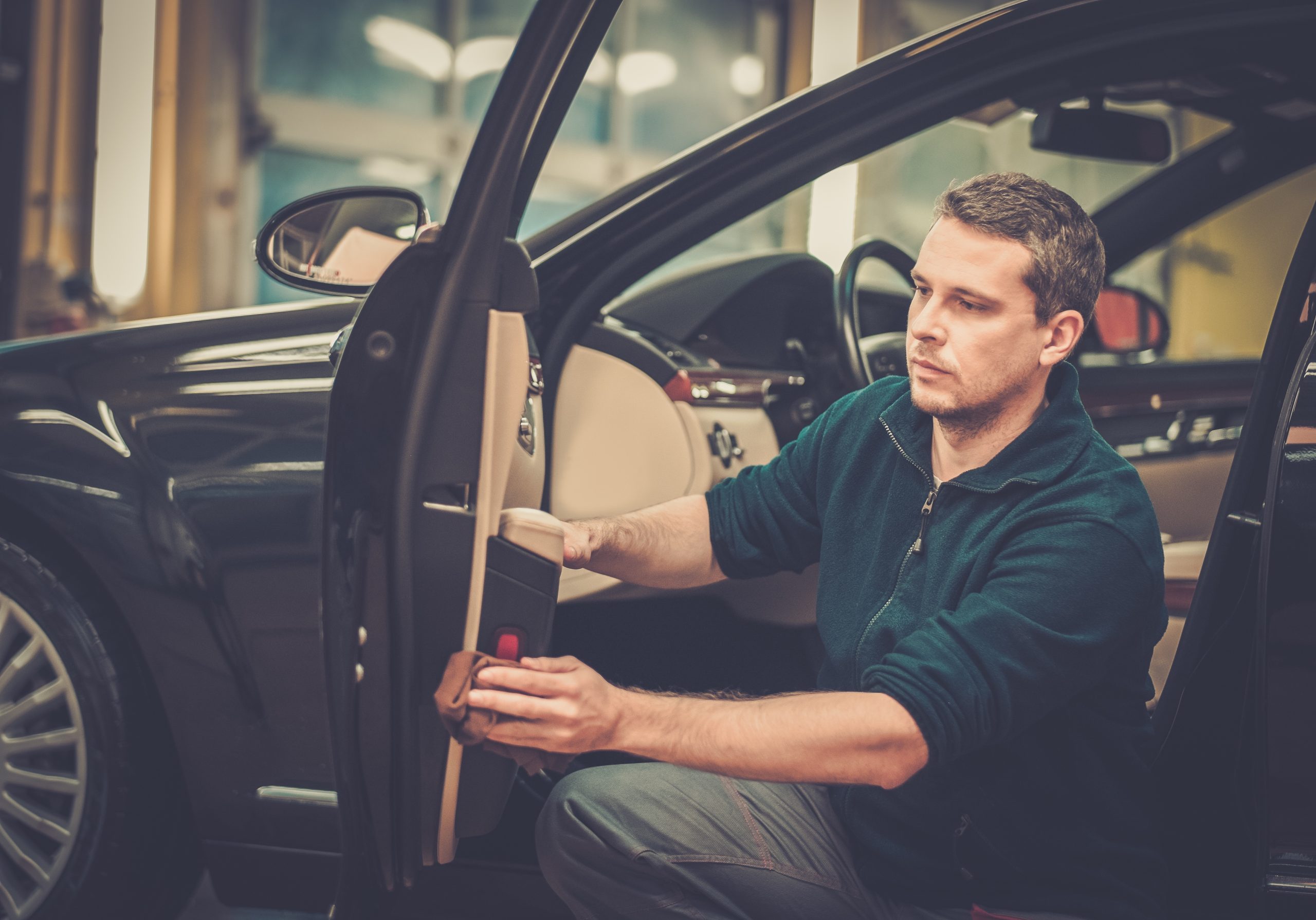Worker on a car wash cleaning car interior